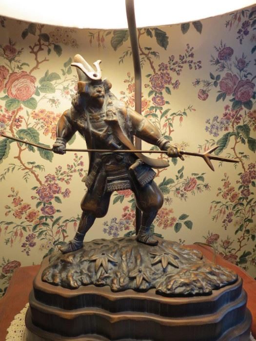 Bronze warrior statue standing on an ornately carved base